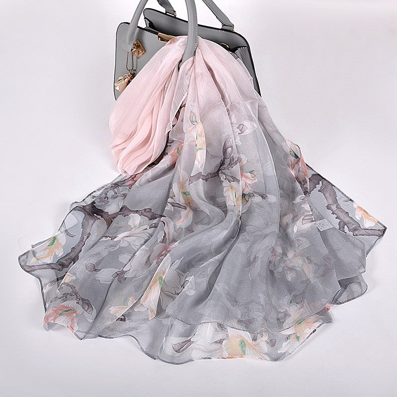 Floral scarf draped over a handbag on a light gray background